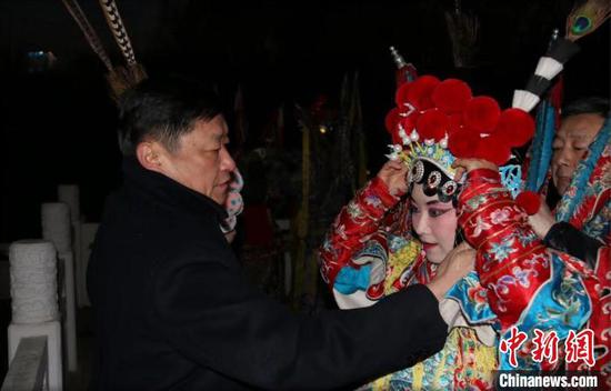 何铁军为上台前的青年演员整理戏服。 受访者供图 何铁军为上台前的青年演员整理戏服。 受访者供图