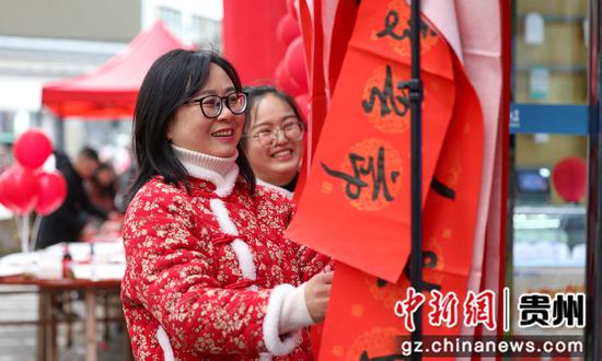 2024年1月21日，在贵州省铜仁市玉屏侗族自治县皂角坪街道紫气山社区，居民在挑选书法志愿者写的春联。